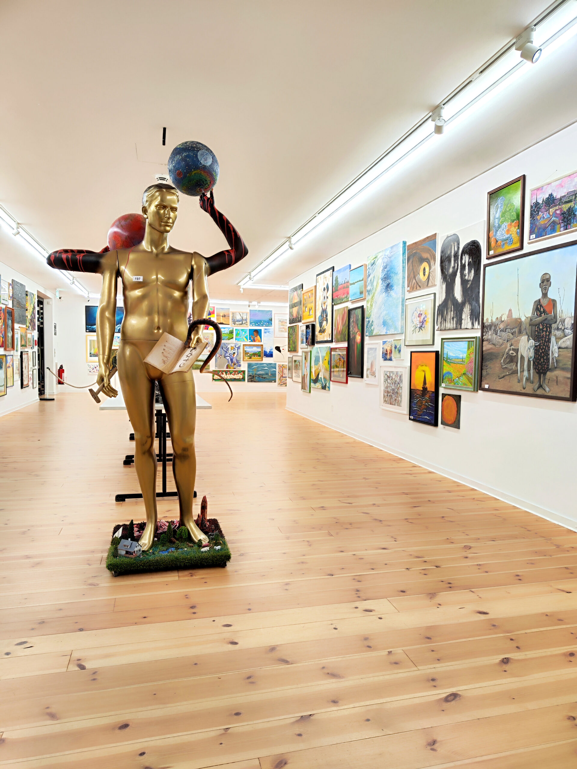 Eine goldene männliche Skulptur vor Bildern in der Kunsthalle.