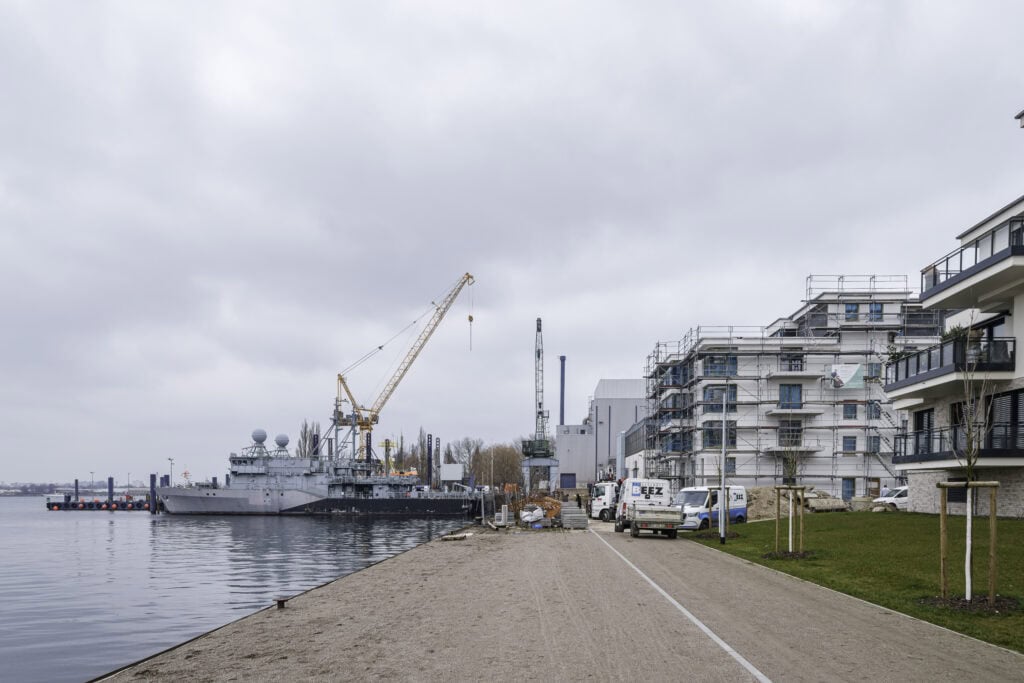 An der Gehlsdorfer Uferkante entstehen zwei Mehrfamilienhäuser in der Helmuth-Mentz-Straße. Die Häuser sind im Bau und eingerüstet. Baufahrzeuge stehen an der Baustelle.