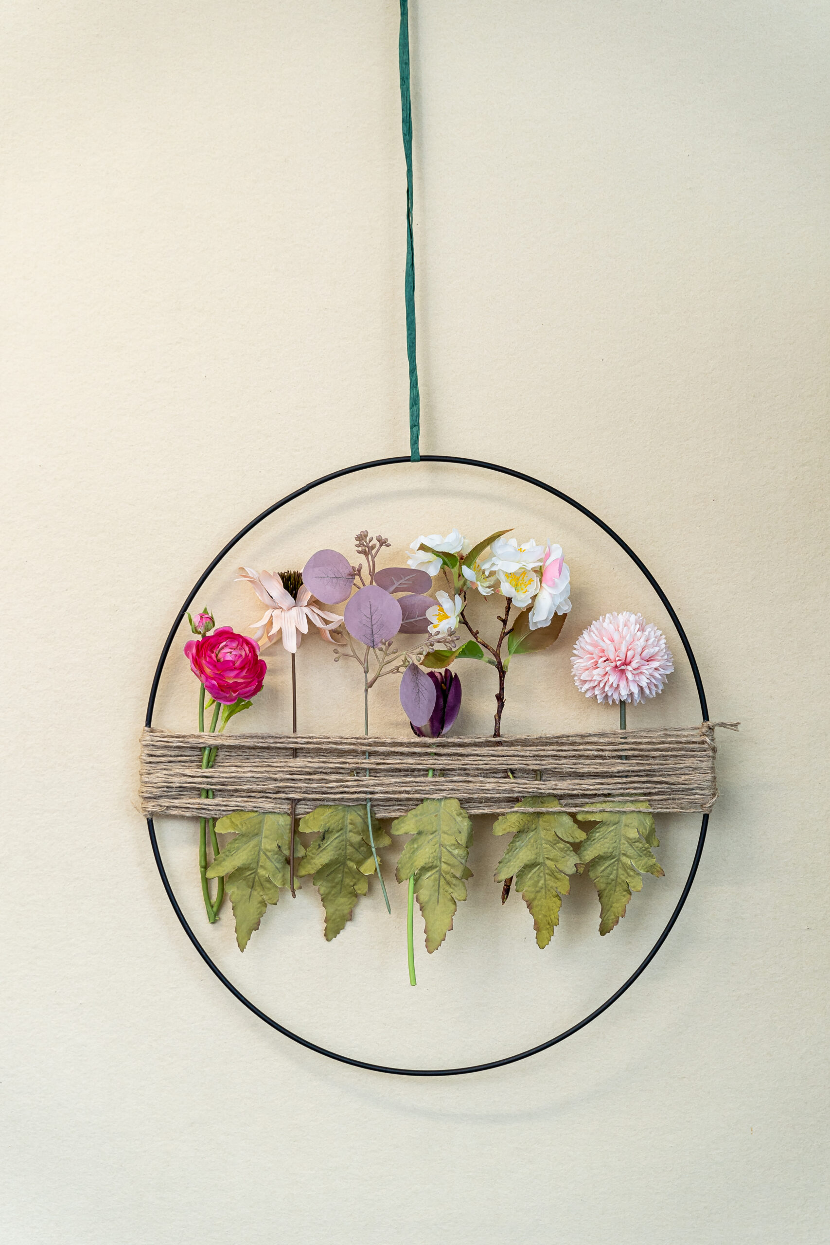 Gute-Laune-Ring Ein Dekoring mit roten, weißen und rosafarbenen Blüten und grünen Blättern an der Wand.