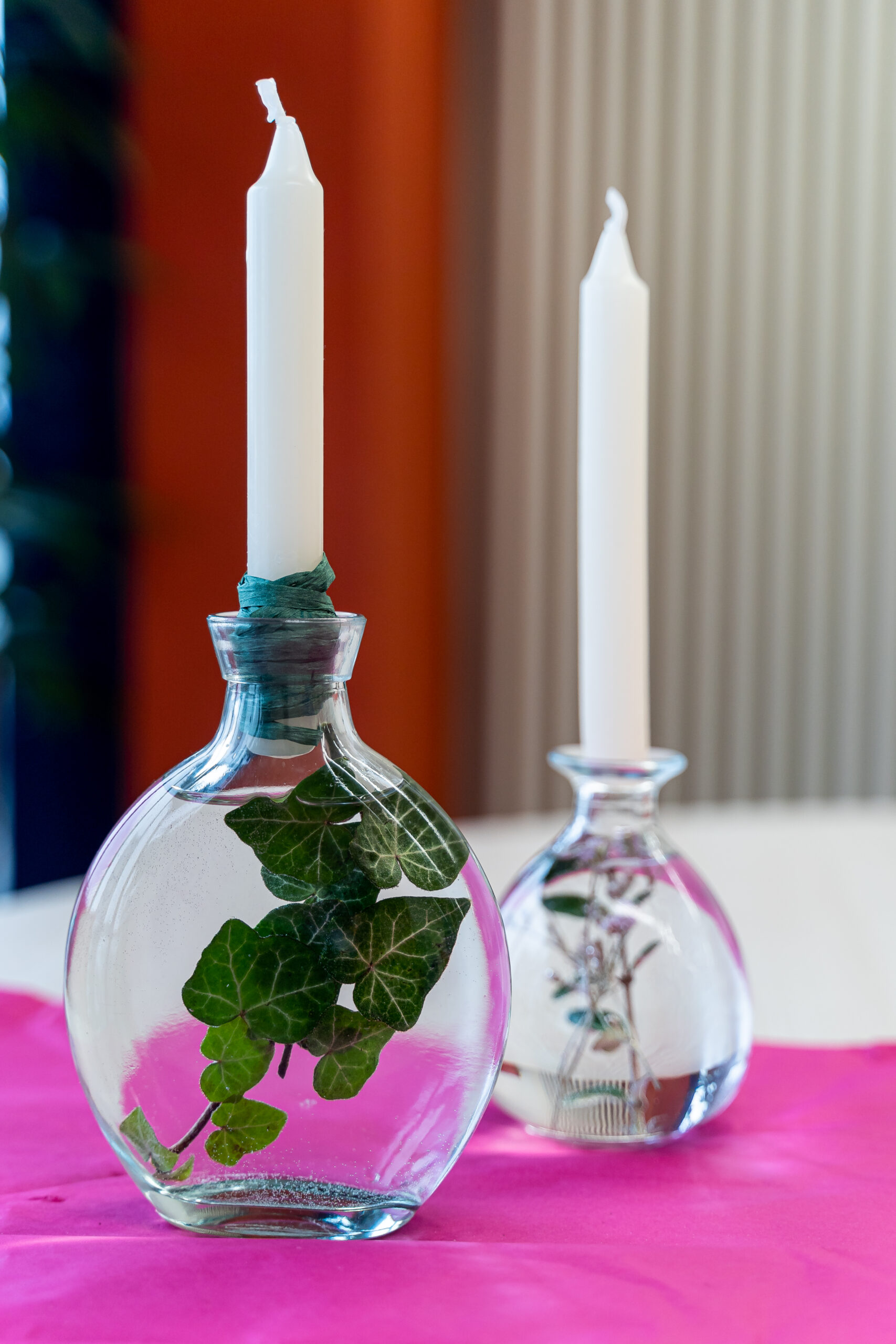Vasen mit Kerzen Zwei Glasvasen mit Efeu und weißen Kerzen.
