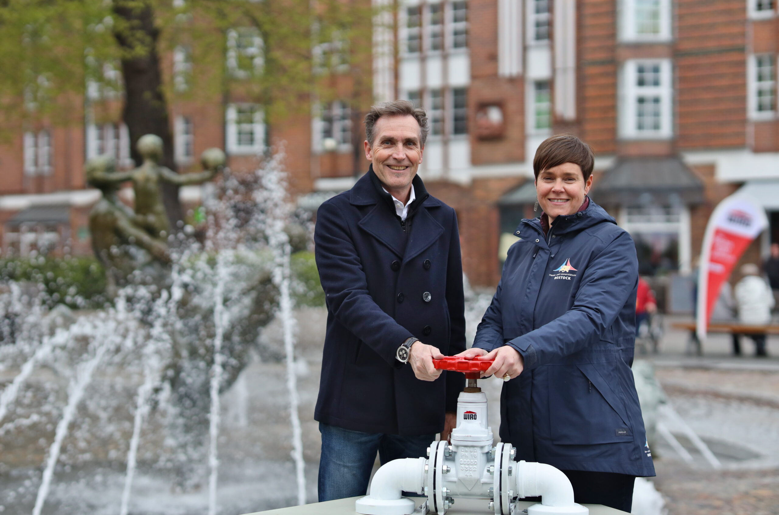 Start Brunnensaison 2024 Ein Foto aus dem Jahr 2024: Oberbürgermeisterin Eva-Maria Kröger und der Vorsitzende der WIRO-Geschäftsführung und Brunnensponsor Ralf Zimlich eröffnen die Brunnensaison und drehen den Hahn auf.