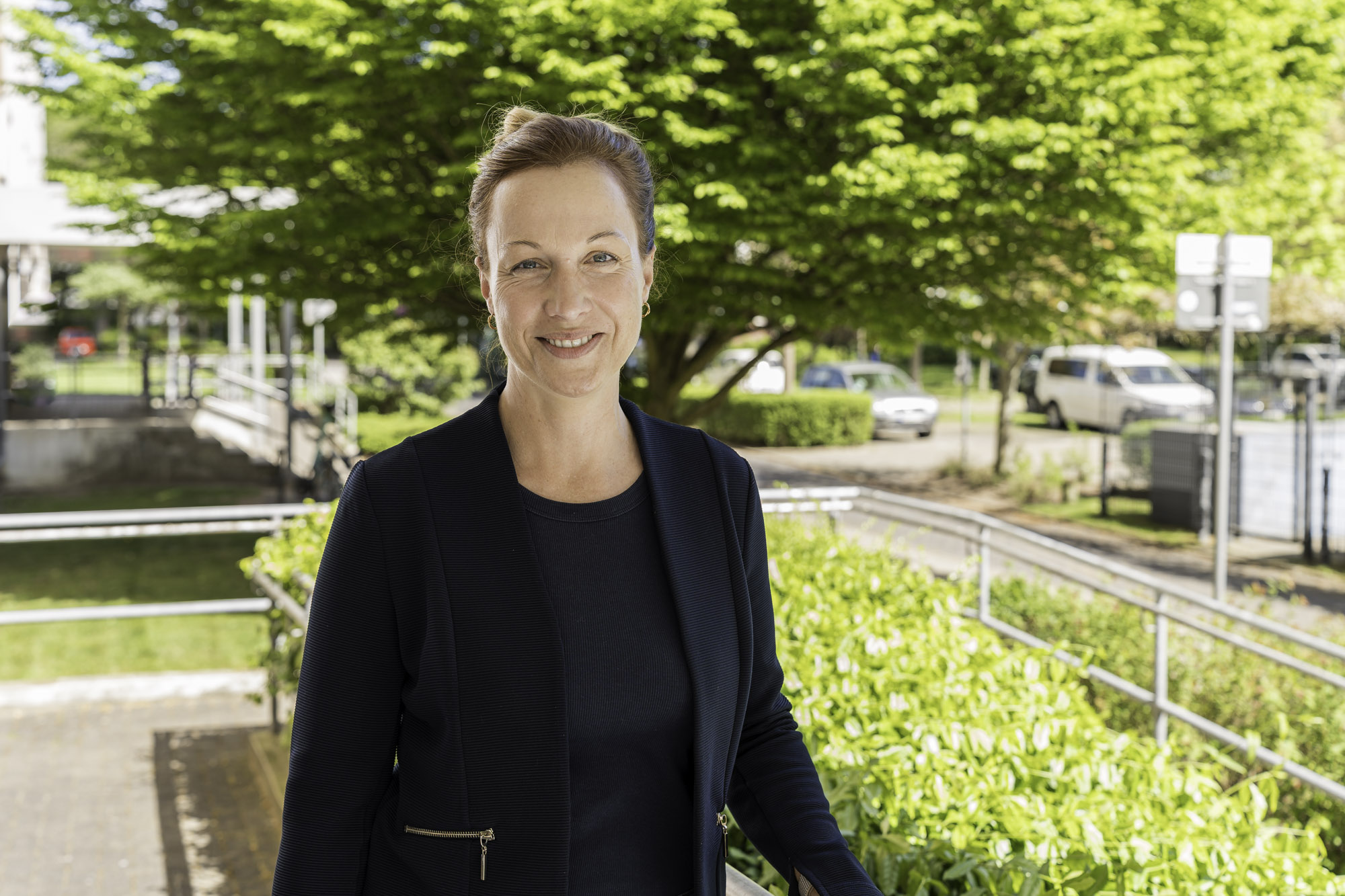 Katharina Krüger, Leiterin Sozialmanagement Katharina Krüger, kastanienbrauner Dutt, lächelnd im dunklen Blazer, ist Leiterin des WIRO-Sozialmanagements.