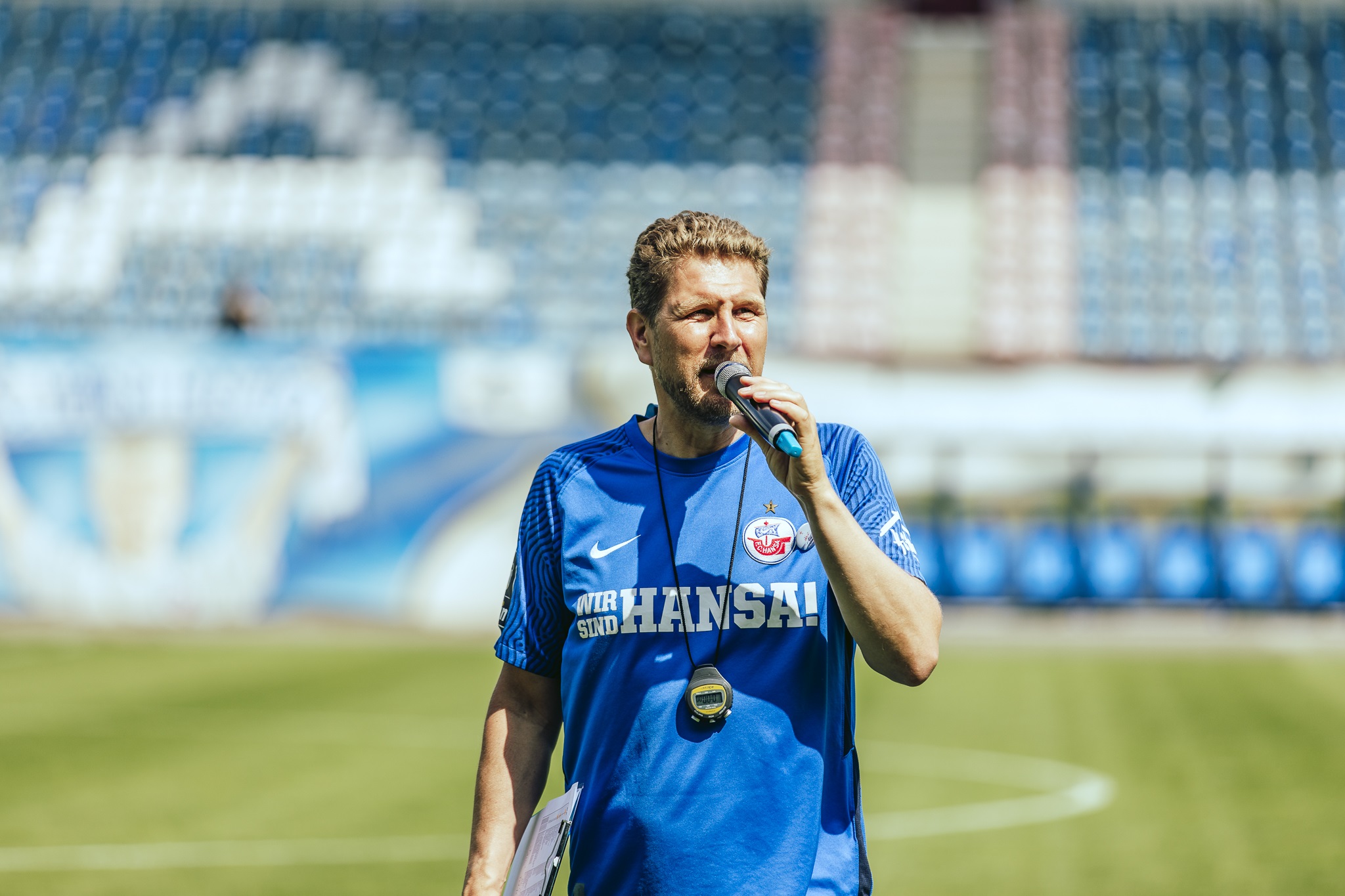 Oliver Schubert Oliver Schubert im blauen Hansa-Trikot und mit Mikro in der Hand im Ostseestadion.