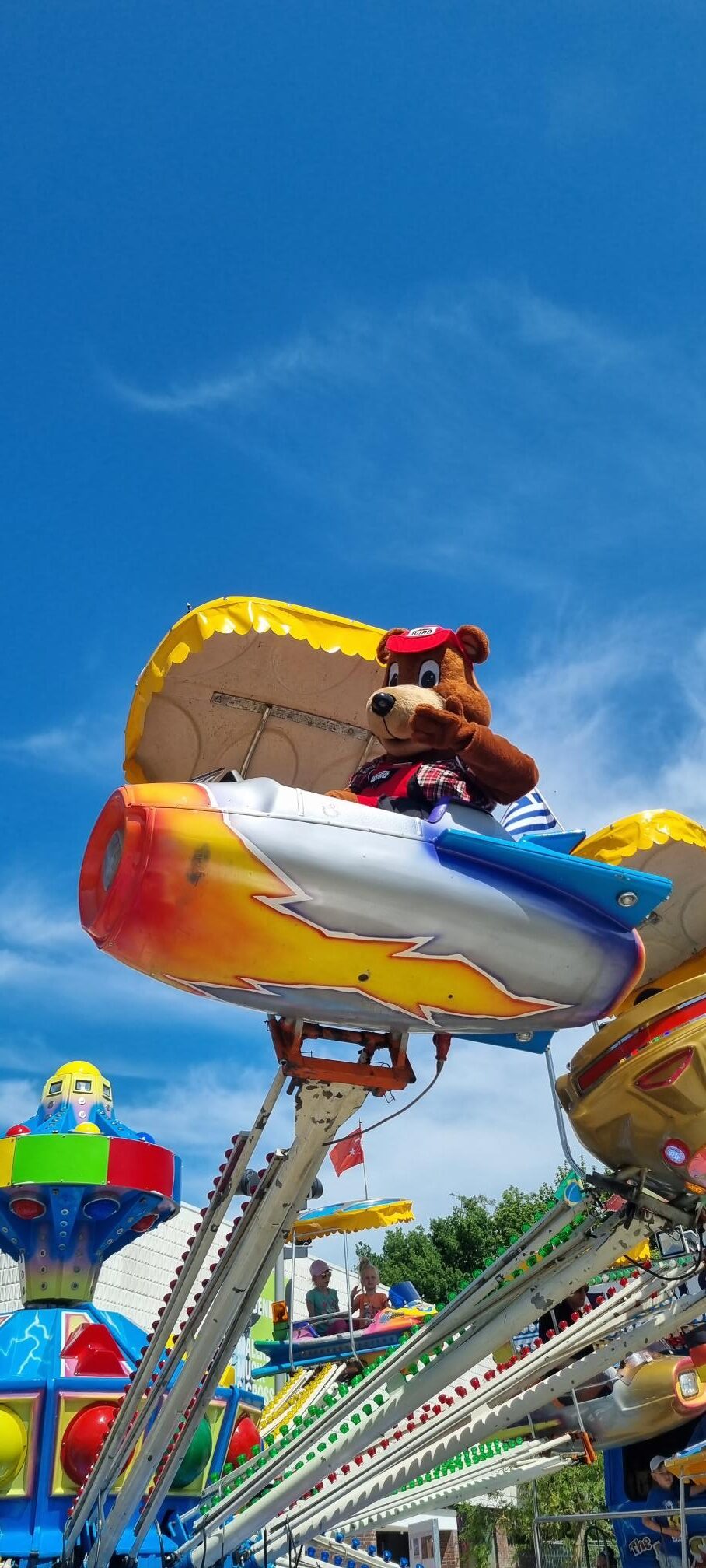 Bodo der Bär im Karussell Bodo der Bär, WIRO-Maskottchen sitzt in einem fliegenden Karussell.