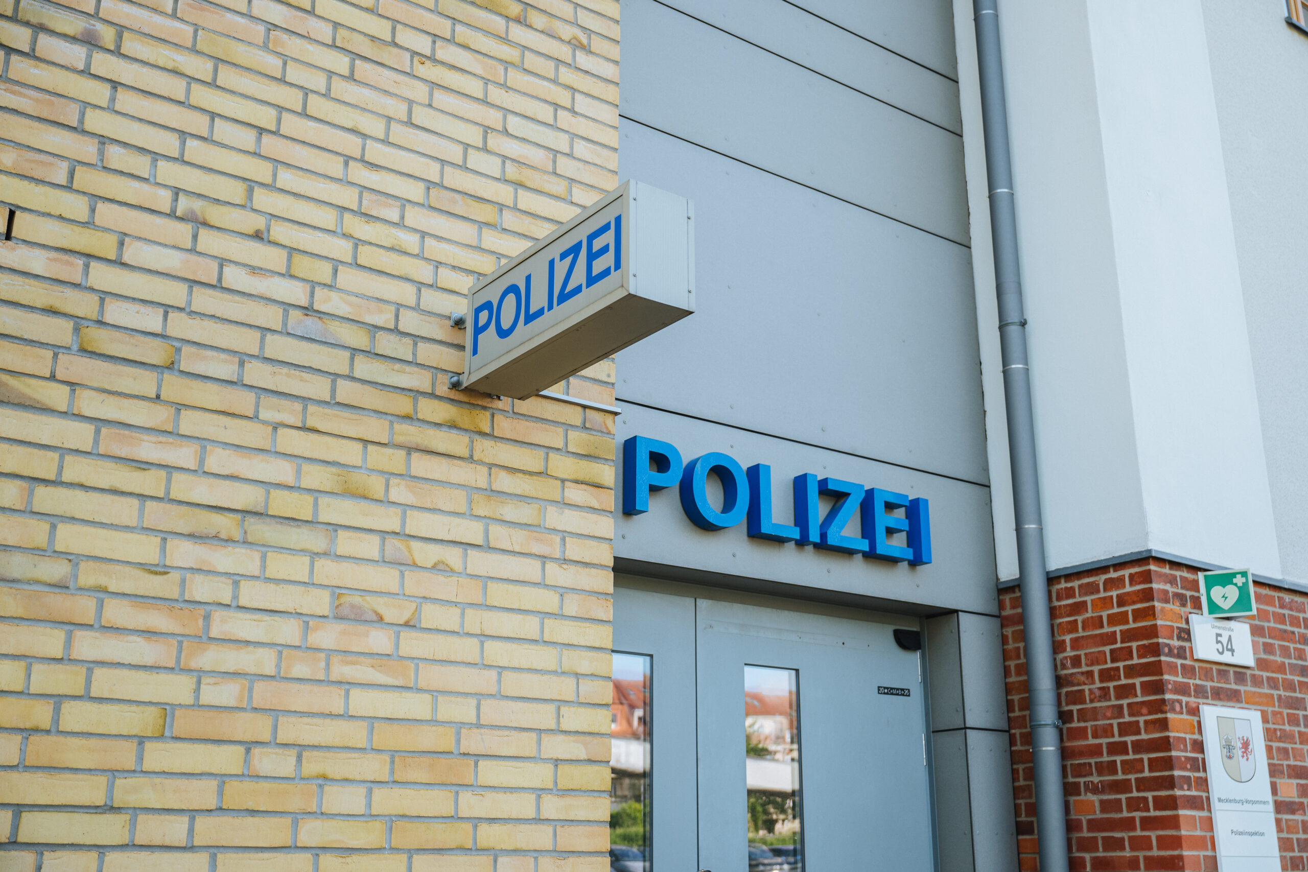 Polizei häusliche Gewalt Eine graue Eingangstür zur Rostocker Polizei mit dem blauen Schriftzug "POLIZEI".