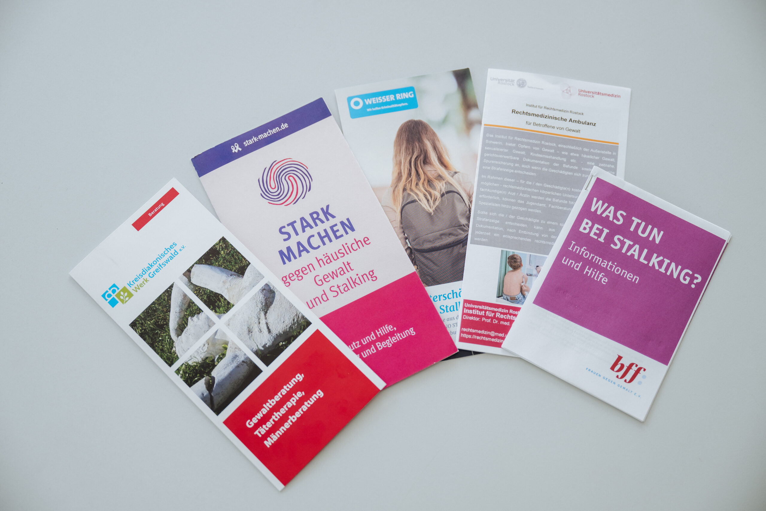 Flyer häusliche Gewalt Fünf Flyer liegen auf dem Tisch, die über die Formen von häuslicher Gewalt aufklären.