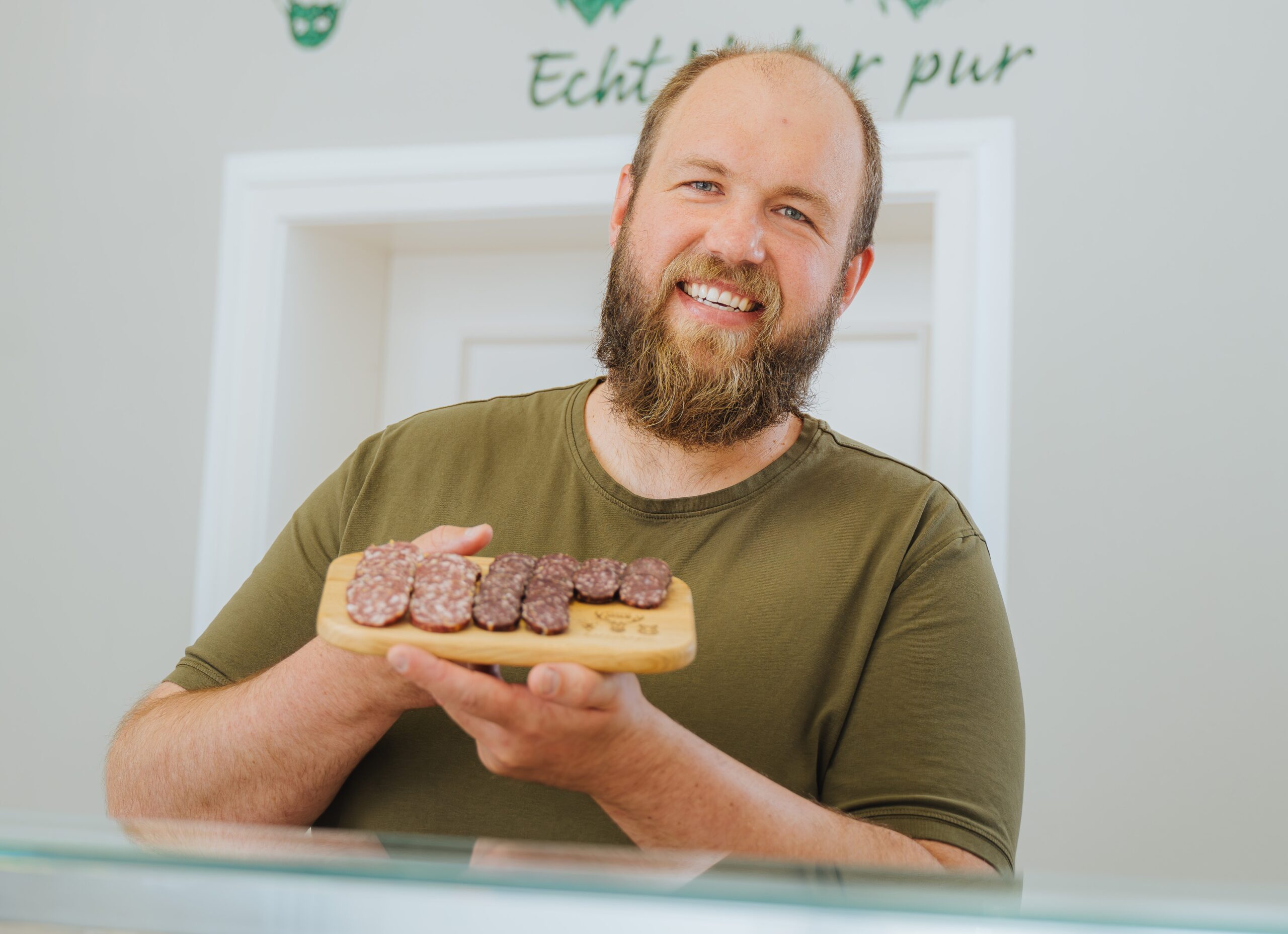 Martin Brodoch ist Mecklenburger, Jäger, Fleischer und Verkäufer von Wildfleisch. Hier hält er ein Brettchen mit Wurstaufschnitt in den Händen.