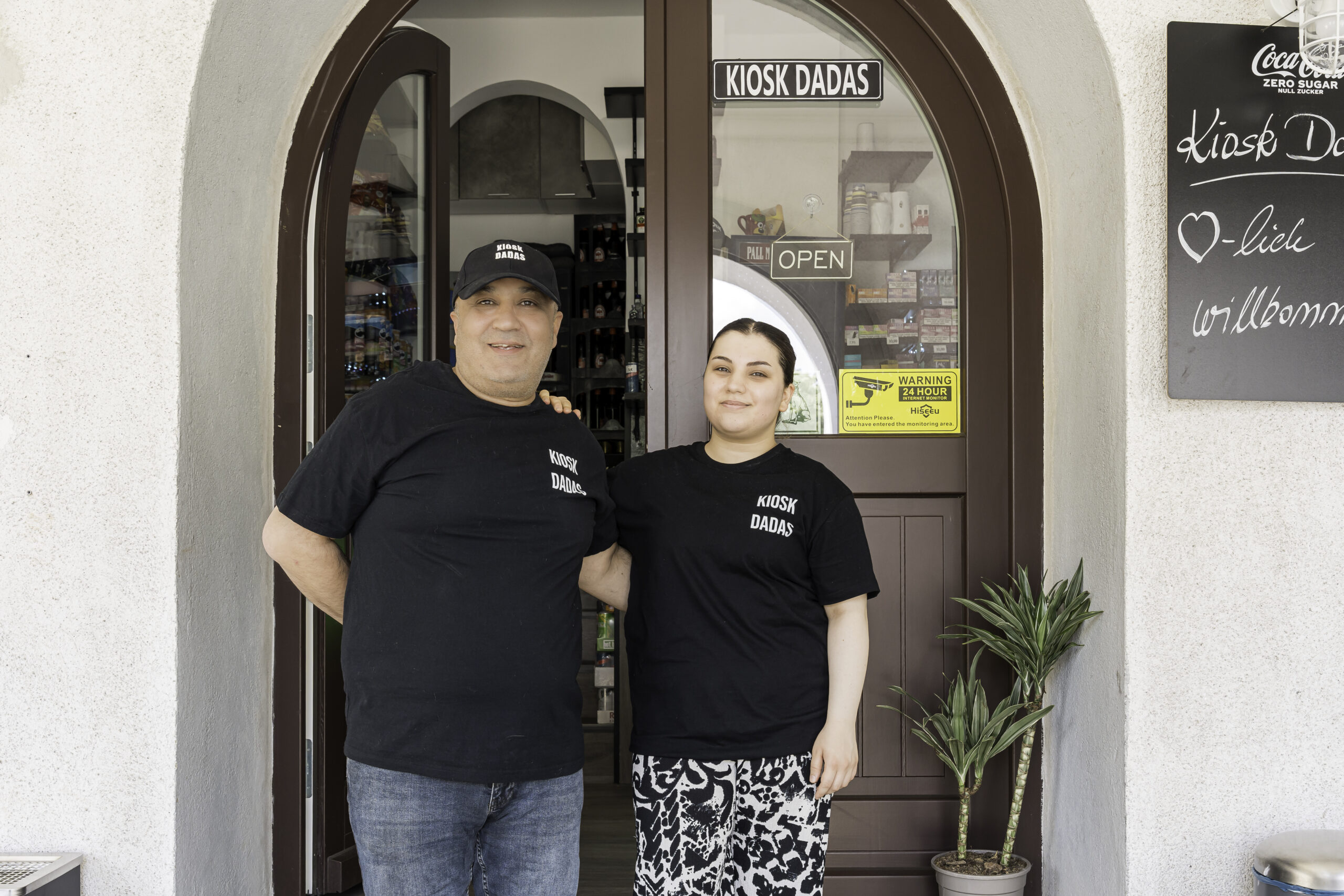Saim Dadas ist gelernter Koch und hat sich mit seinem Kiosk in der Großen Mönchenstraße einen Traum erfüllt. Tochter Asli Ecem Dadas hilft dabei und steht ihrem Vater auch im Eingangsportal des Kiosk zur Seite. Beide tragen schwarze Shirts mit der Aufschrift Kiosk Dadas.