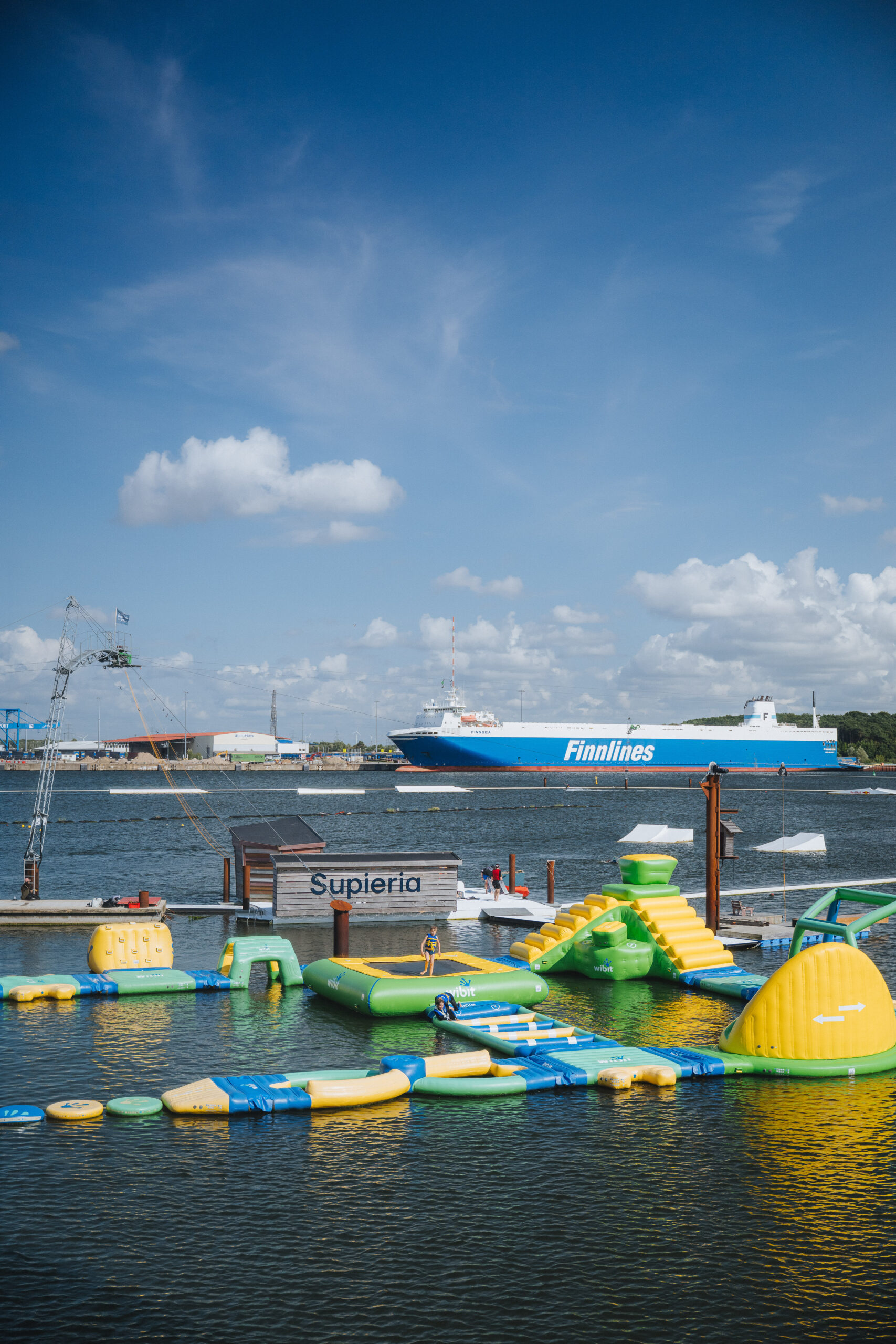 Die Wakeboard- und Wasserskianlage Supieria vor einer Finnlines-Fähre am Warnowstrand im IGAPark.