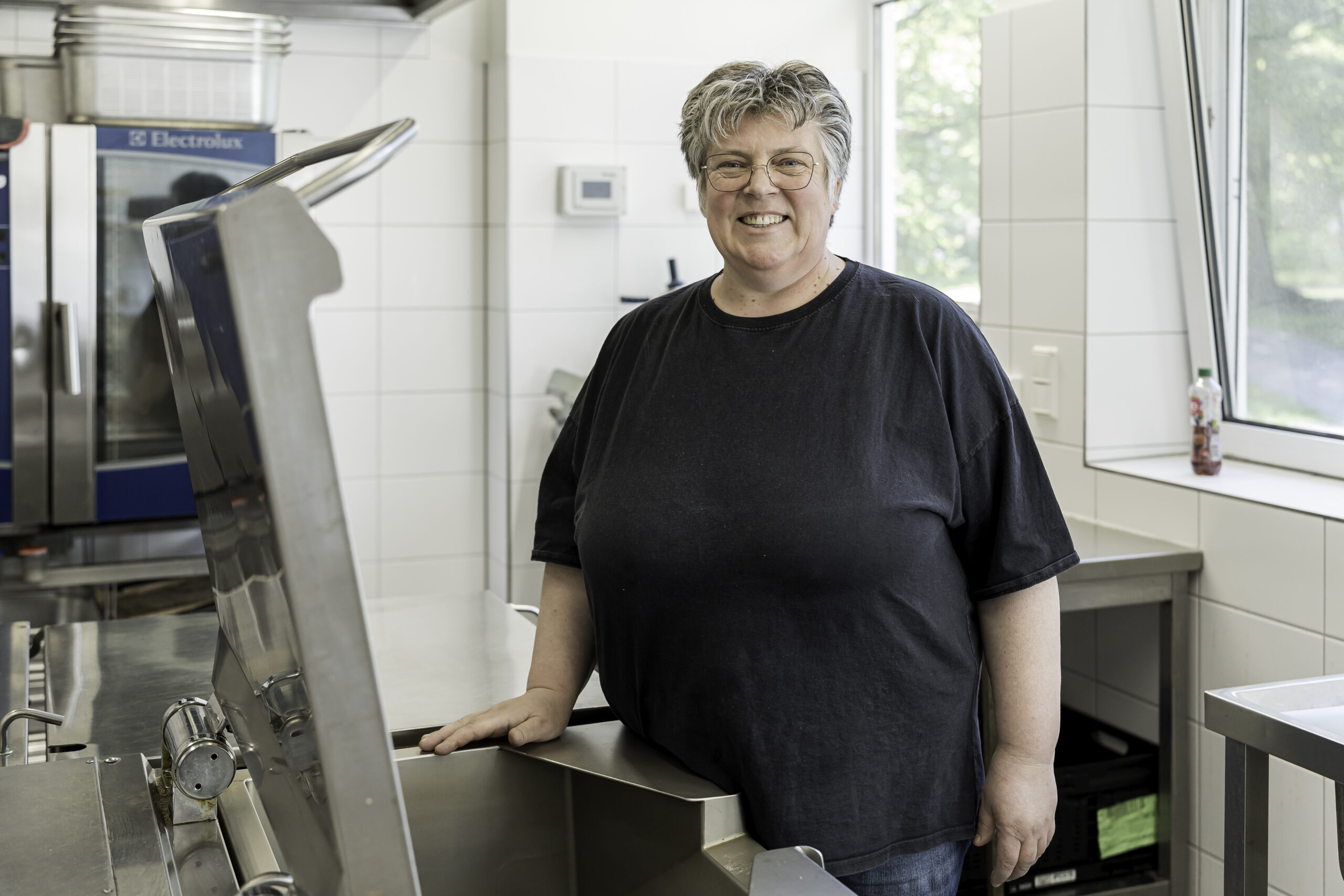 Corinna Johnsen Suppenküche Corinna Johnsen, kurze blonde Haare, Brille und schwarzes T-Shirt arbeitet seit 15 Jahren in der Suppenküche und kennt viele Besucher.