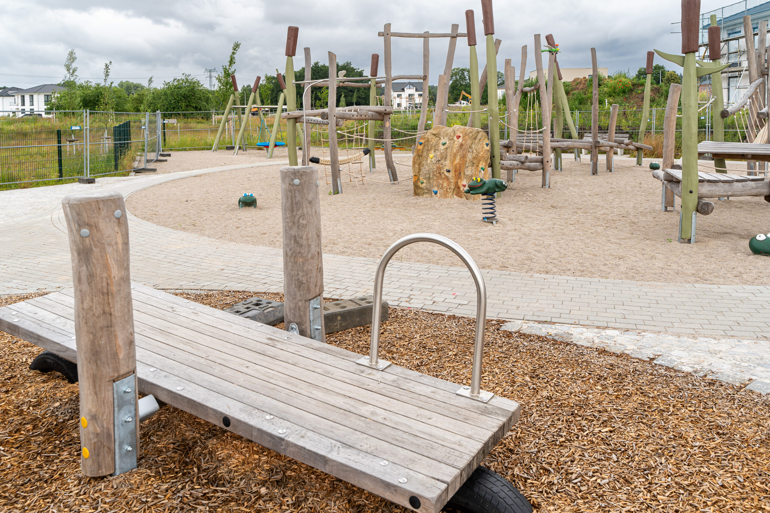 Spielplatz Kiefernweg DOMUSIMAGES Spielplatz im Rostocker Kiefernweg mit Holz-Klettergeräten und Frosch-Wippe.