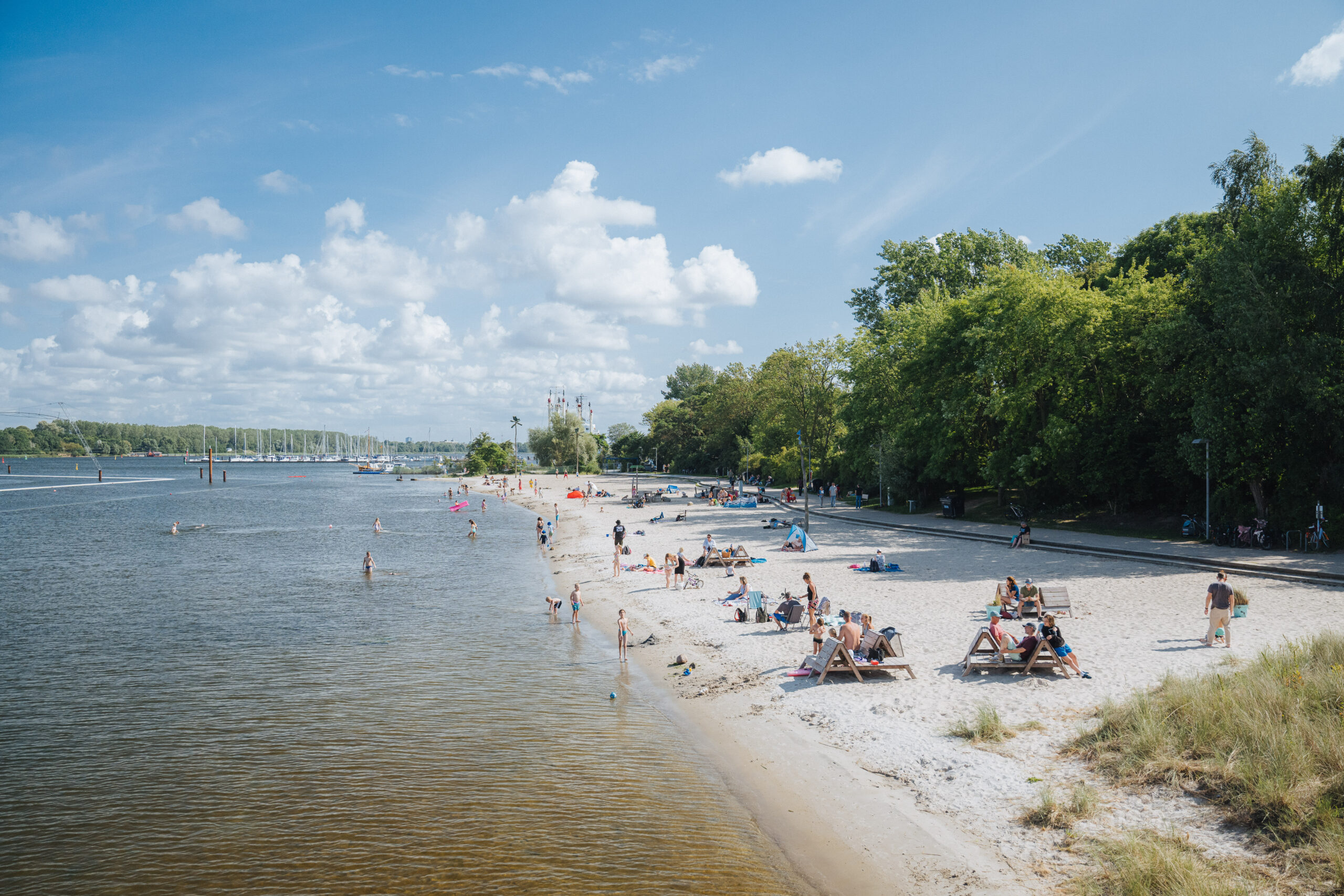 Badegäste und Sonnenanbeter am weißen Warnowstrand im grünen IGAPark.