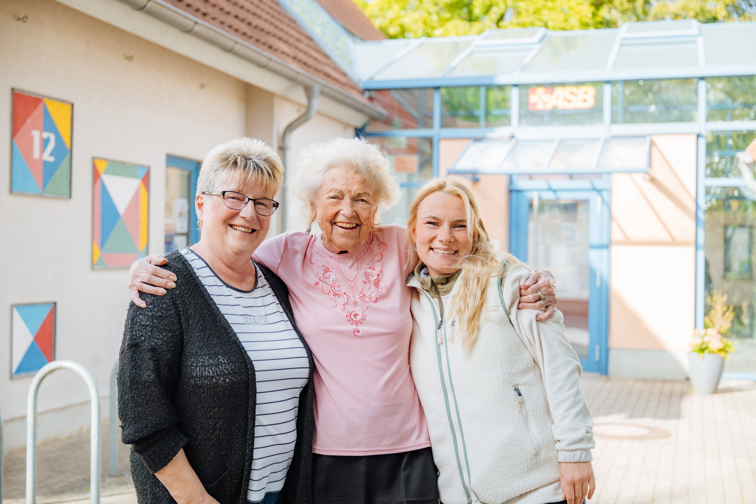 Ein richtig gutes Team: Ehrenamtlerin Hannelore Stimm, kurze blonde Haare, Brille, mit der 98-jährigen fröhlichen Dame Gerda Holz (li.) und Lea Freese, Mitarbeiterin vom SBZ Schmarl, die Ehrenamtler und betagte Einwohner zusammenbringt.