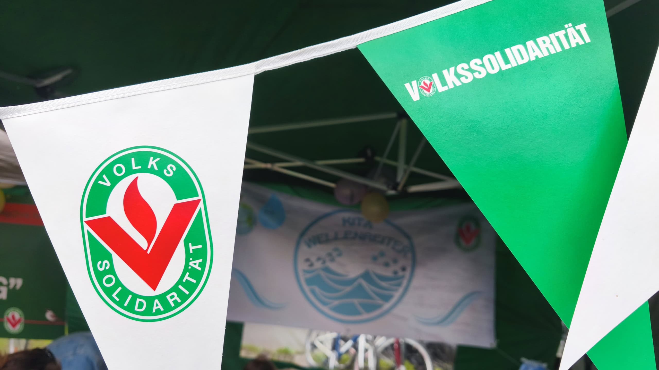 Grün-weiß-rote Wimpel mit der Aufschrift und dem Logo der Volkssolidarität.