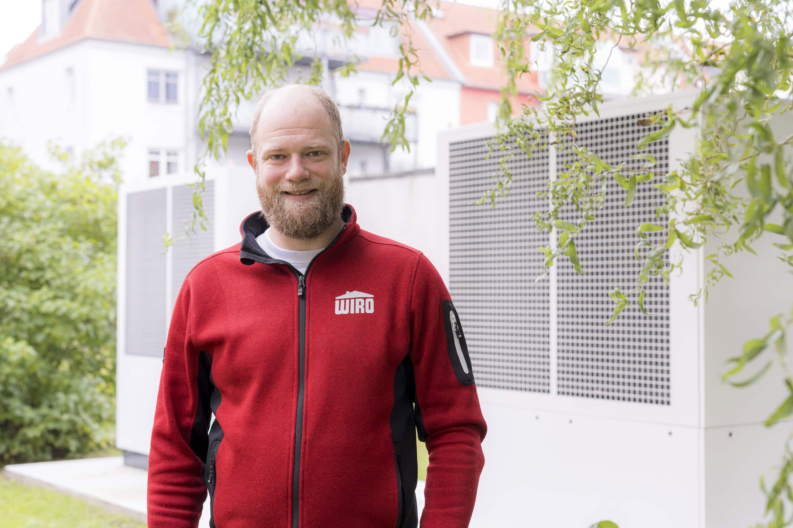In der Dänischen Straße 12 bis 14 in Warnemünde hat das Team Modernisierung mit Meister Meikel Olivera Lopez - Vollbart, rote WIRO-Jacke - eine neue Heizzentrale gebaut, eine Hybridanlage aus Luft-Wasser-Wärmepumpe und Gasgerät.