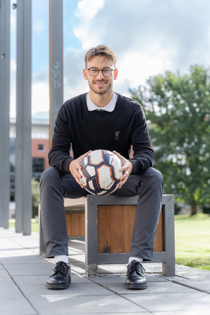 Carlo Lange, ein sportlicher junger Mann mit einem Fußball in den Händen und grau-schwarzer Anzugsordnung hat nach seiner Ausbildung bei der WIRO noch viel vor. Er studiert Bauingenieurwesen an der Uni Rostock.
