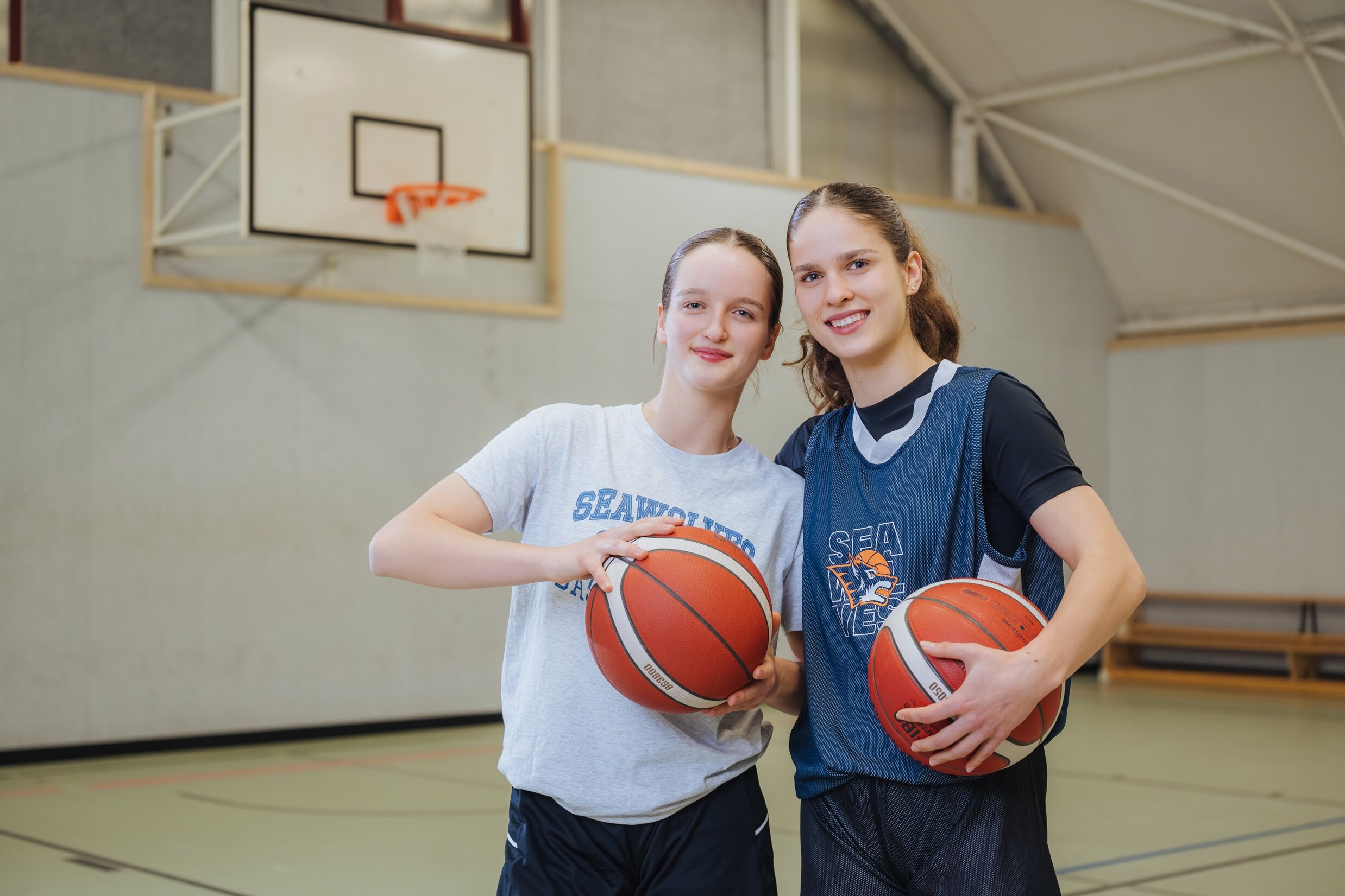 Carolina und Danika Broschwitz, 19 und 16 Jahre, sieht man wie hier in der Sporthalle selten getrennt. Die brünetten Schwestern gehen auf dieselbe Schule, und sie teilen ihre Leidenschaft: Seit der Grundschulliga spielen sie Basketball bei den Rostock Seawolves. Jede von ihnen hält einen der orangefarbenen Bälle in den Händen.