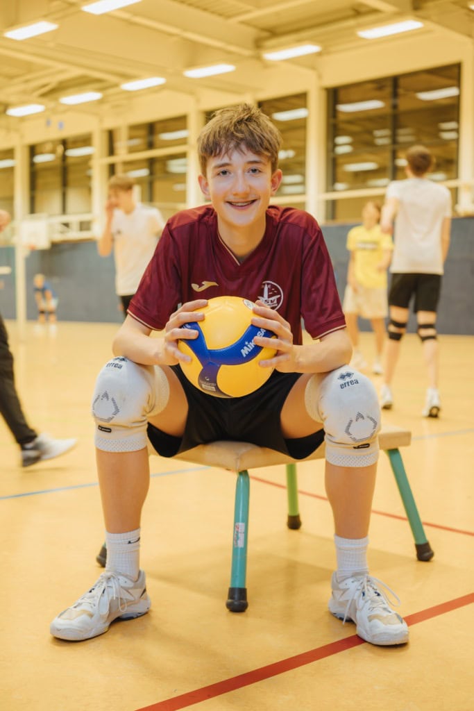 Der brünette Lukas Sanftleben überragt die meisten Gleichaltrigen um viele Zentimeter. Mit 14 Jahren misst er einen Meter einundneunzig, was man ihm selbst im Sitzen mit einem Ball in der Hand in der Halle ansieht. Das ist in seinem Sport sehr nützlich, um schnelle Volleybälle beim SV Warnemünde zu spielen.