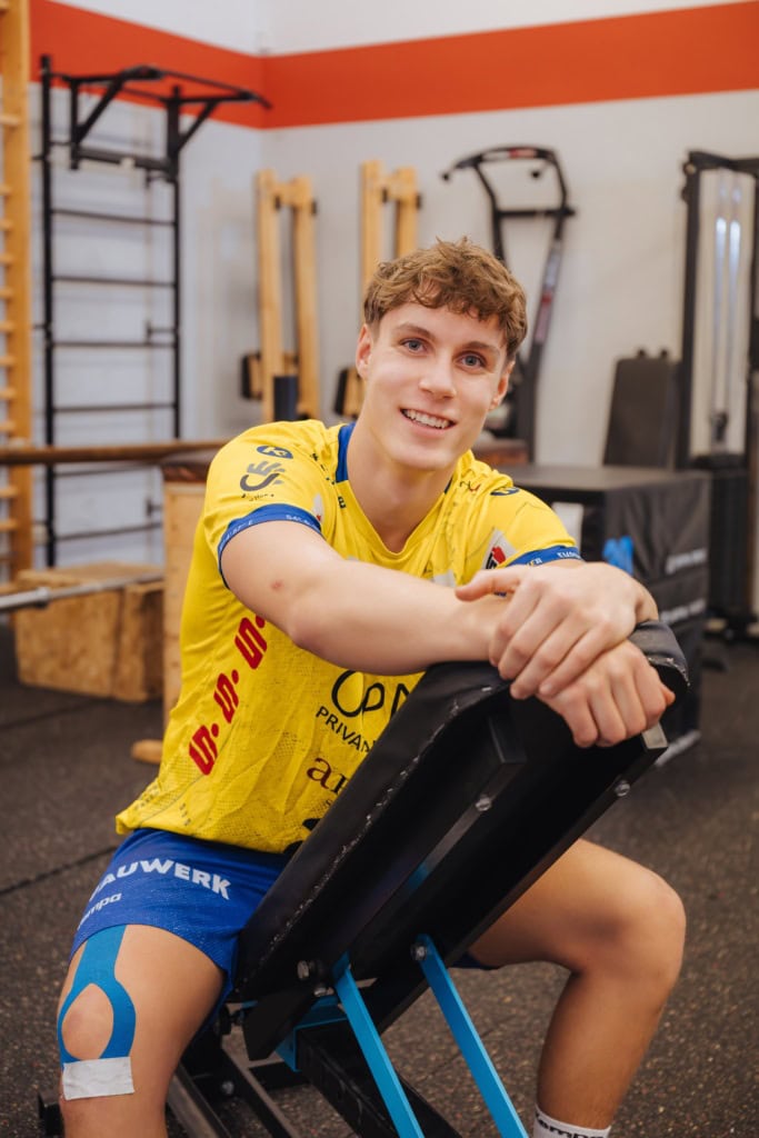 Der brünette Philip ist Handballer. Seit der 5. Klasse geht er auf die Sportschule, Heute spielt der 18-Jährige mit seiner Mannschaft in der A-Jugendbundesliga von HC Empor - zu erkennen an seinem gelb-blauen Trikot, in dem er im Trainingsraum rittlings auf einem Sportgerät sitzt.