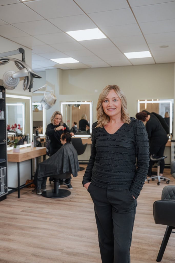 Die blonde Friseurmeisterin Beatrice Grunwald - ganz in schwarz gekleidet - in ihrem Salon in der Rostocker Ulrich-von-Hutten-Straße.