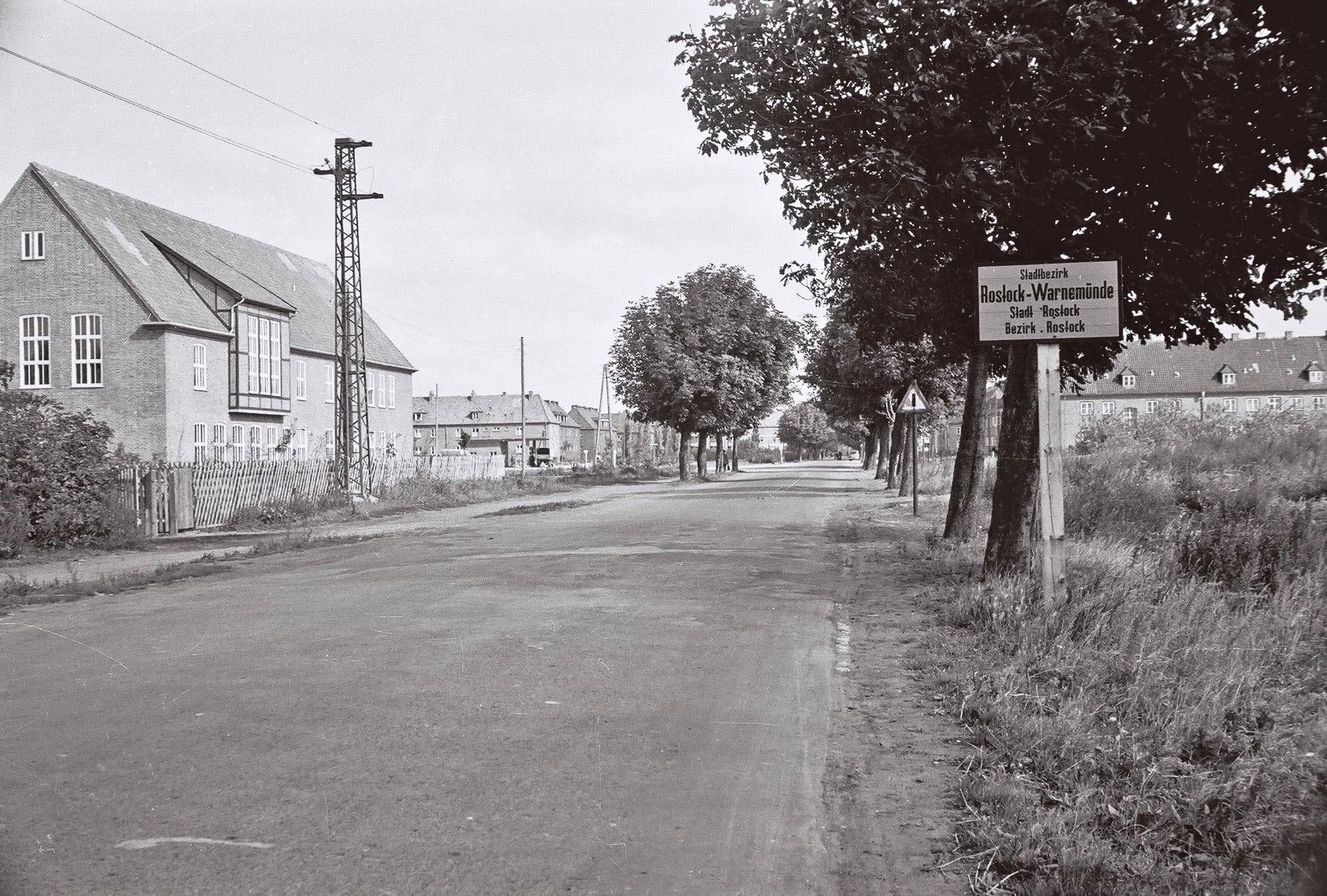 Blick auf die Rostocker Straße früher: So sah der Ortseingang von Warnemünde 1956 aus. Ein altes Ortseingangsschild ist zu sehen mit der Aufschrift: Stadtbezirk Rostock-Warnemünde
