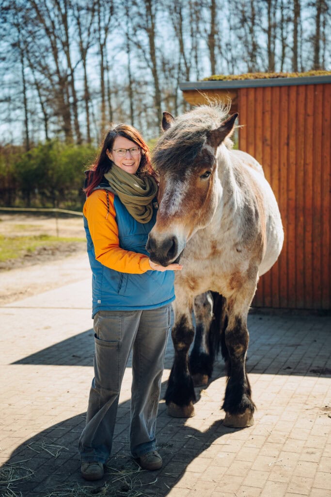 ASB-Kinderbauernhof-Leiterin Anne- Kathleen Schäfer mit einem blond-braunen Kaltblüter an ihrer Seite.