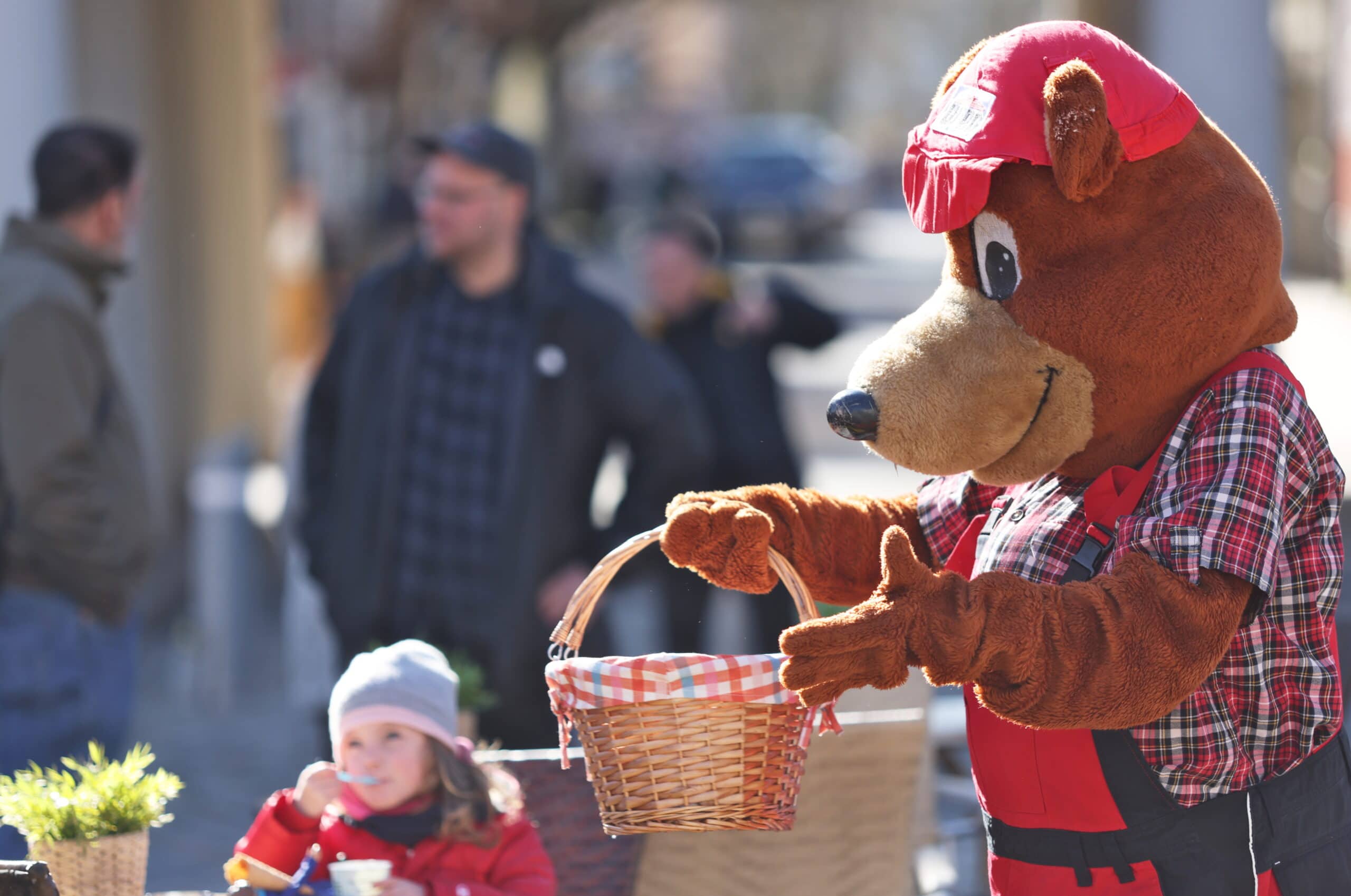 im Vordergrund WIRO-Maskottchen Bodo verschenkt Süßigkeiten bei der Eröffnung der Rostocker Brunnensaison, im Hintergrund Passanten (Foto: WIRO/Danny Gohlke)