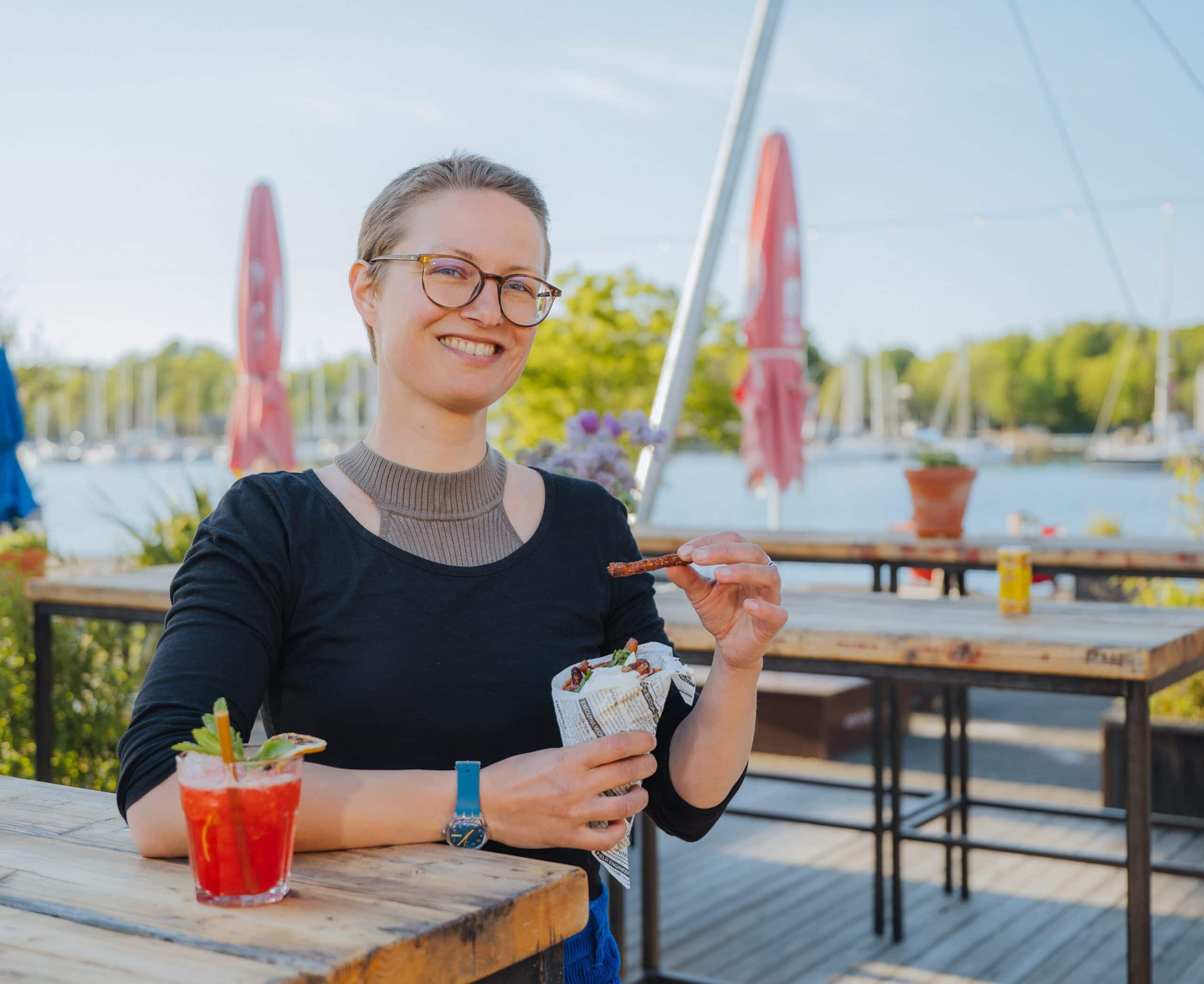 Helene Nozon vom Hafendommel-Team mit kühlem Getränk und Pommes in der Hand macht Sommerlaune.