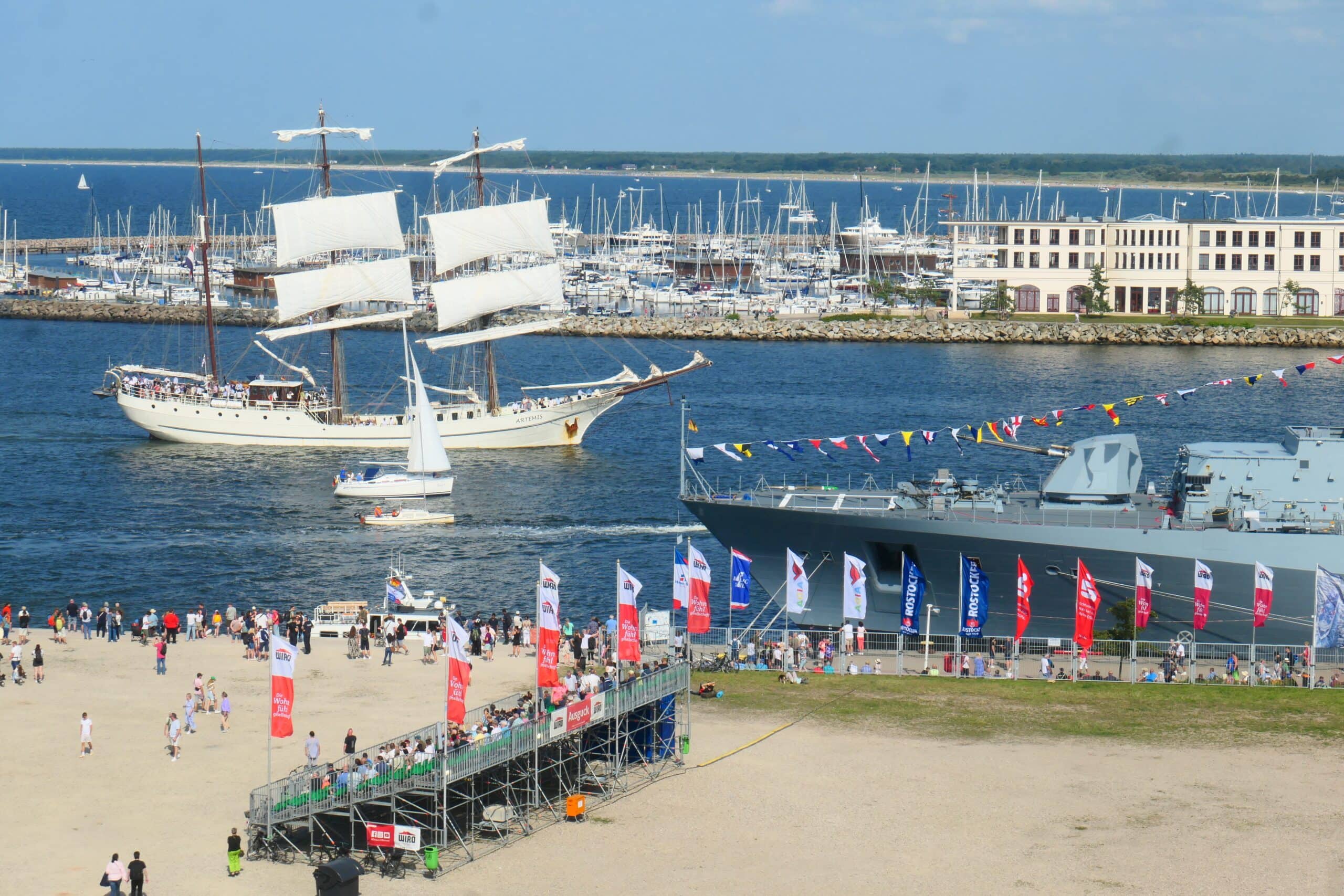 Blick auf die Warnemünder Mittelmole mit WIRO-Tribüne und Schiffen im Seekanal zur Rostocker Hanse Sail 2025