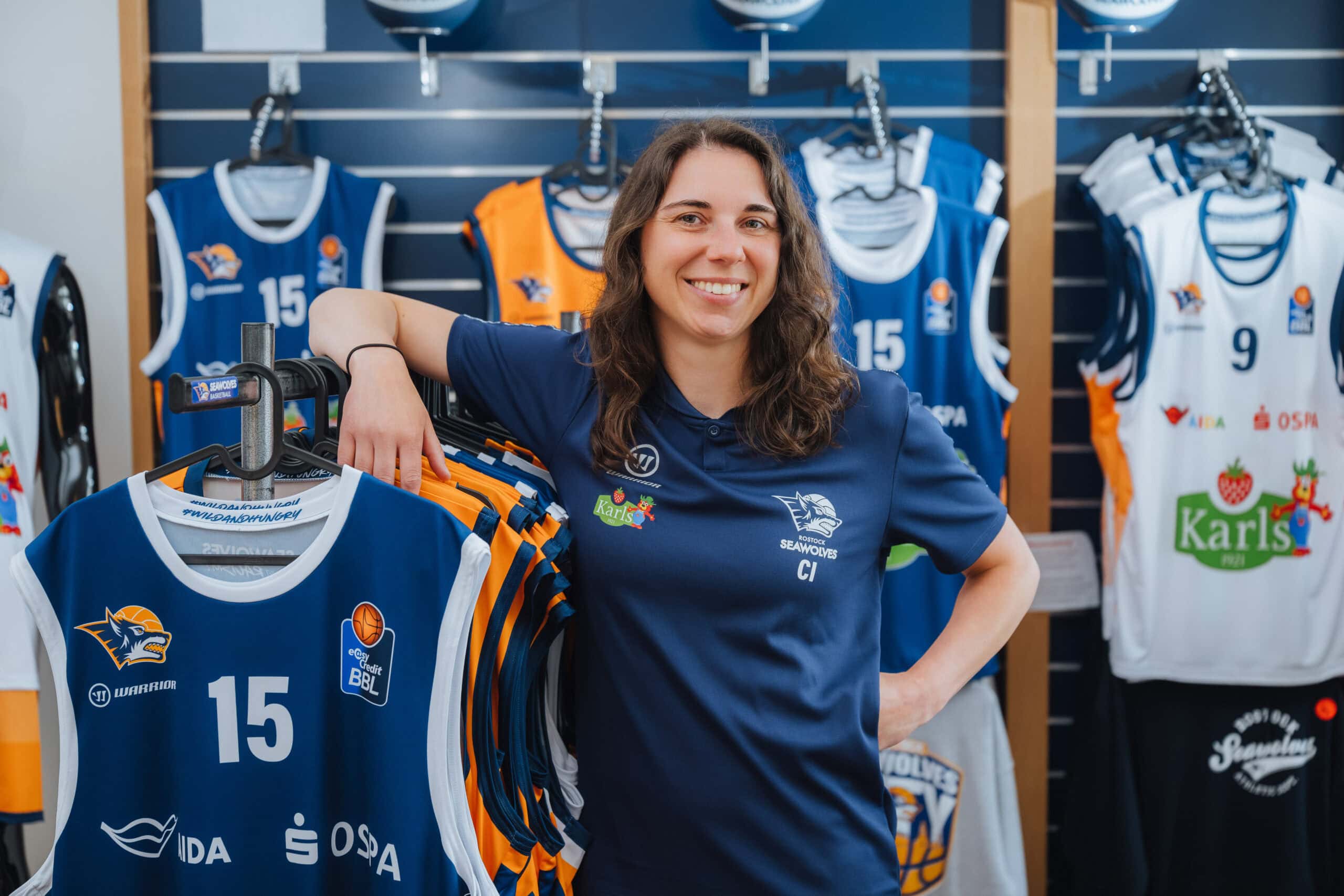 Saisonstart bei den Seawolves. Für die neuen Spieler, vor allem die aus den USA, ist vieles fremd: Sprache, deutsche Sitten, die komplizierte Bürokratie. Damit sie sich mit Unbequemlichkeiten nicht herumschlagen müssen, sondern voll und ganz aufs Basketballspielen konzentrieren können, gibt es Carolin Imhof. Die 36-jährige Teammanagerin sorgt dafür, dass sich die Jungs in Rostock wie zu Hause fühlen.